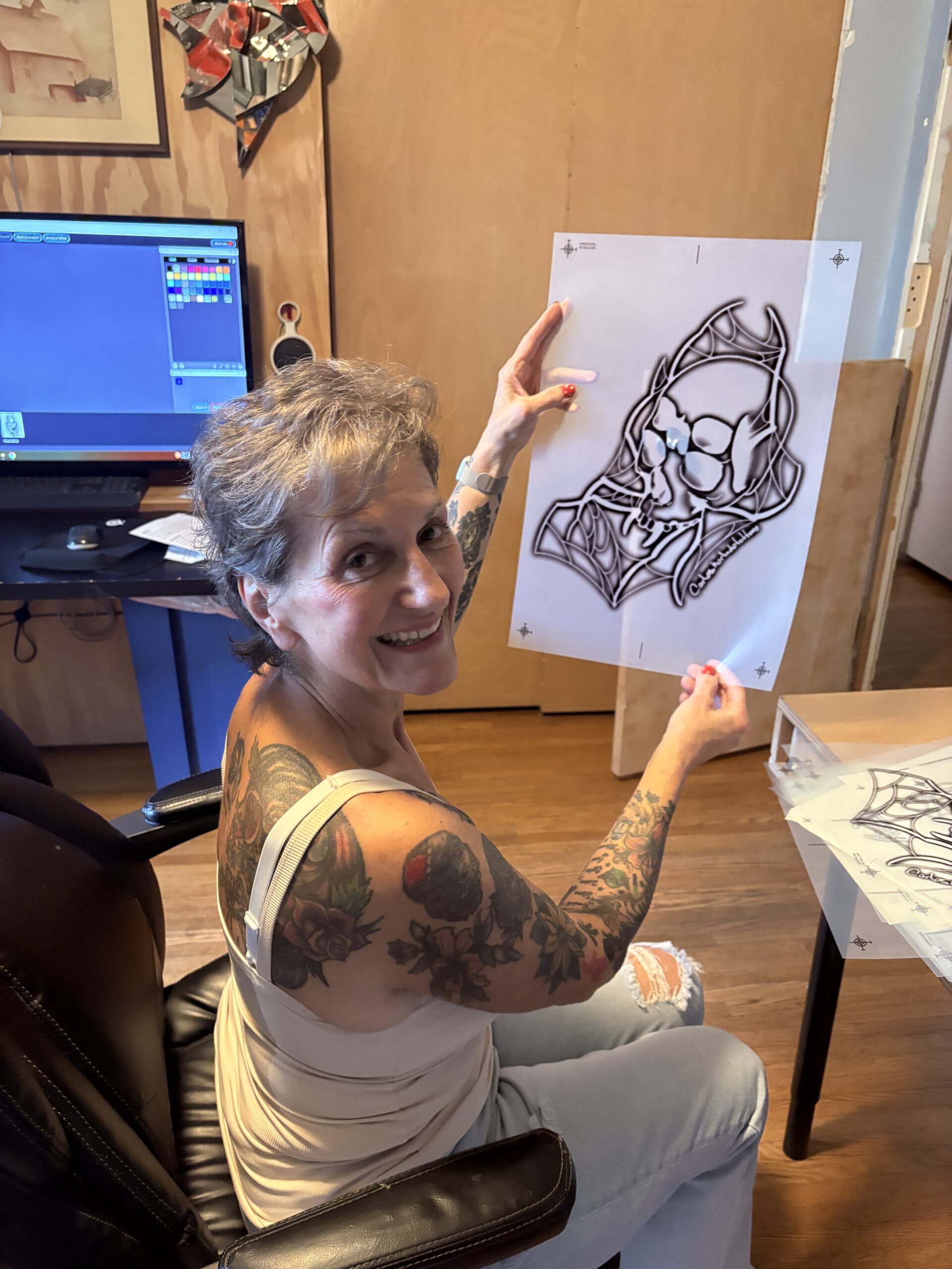 Rhonda smiling while holding a bold black-and-white drawing in her studio—an artist expressing resilience through art.