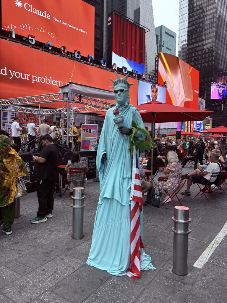 Street performer dressed as the Statue of Liberty wearing sunglasses in Times Square, New York City