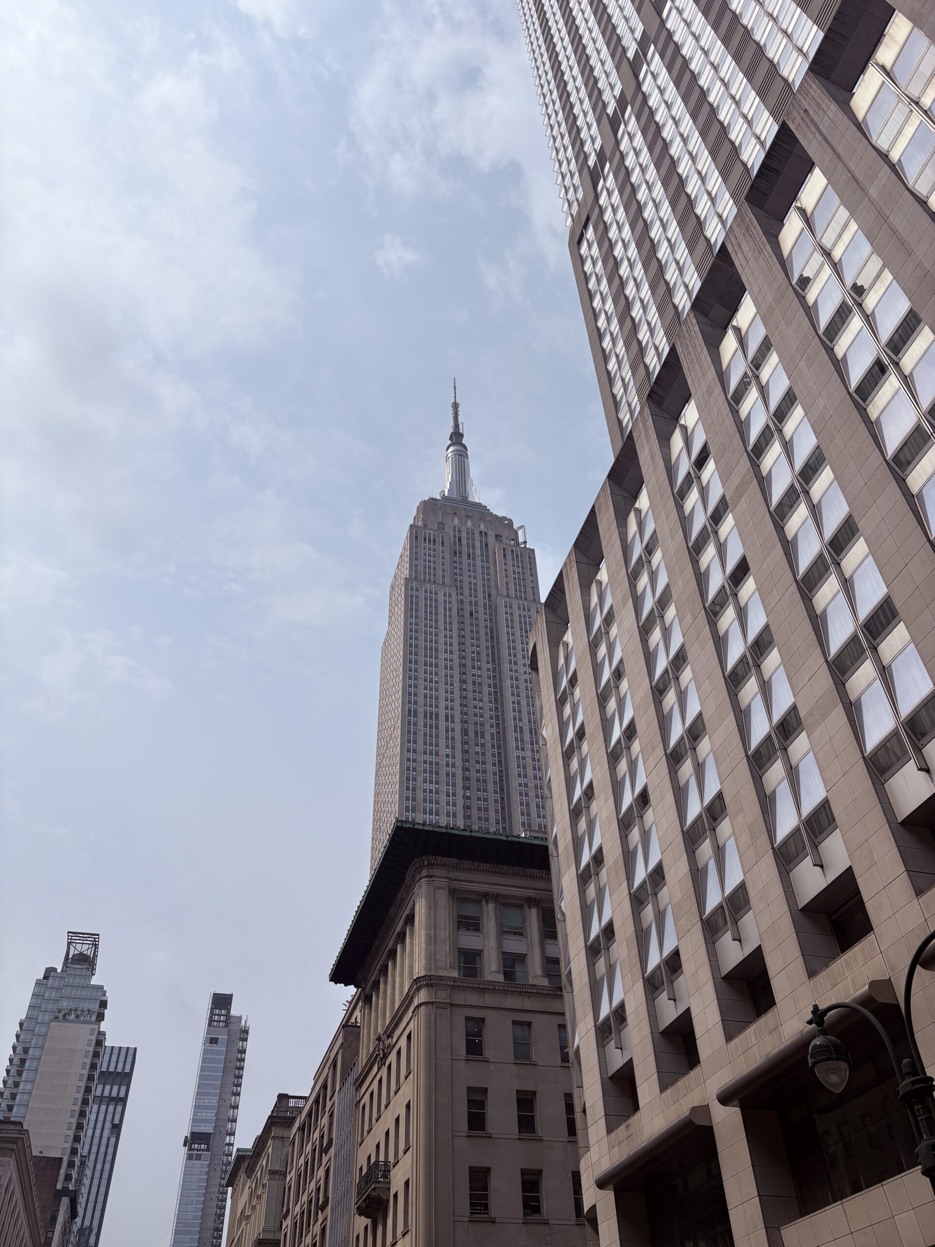 View of the Empire State Building surrounded by other buildings in New York City.