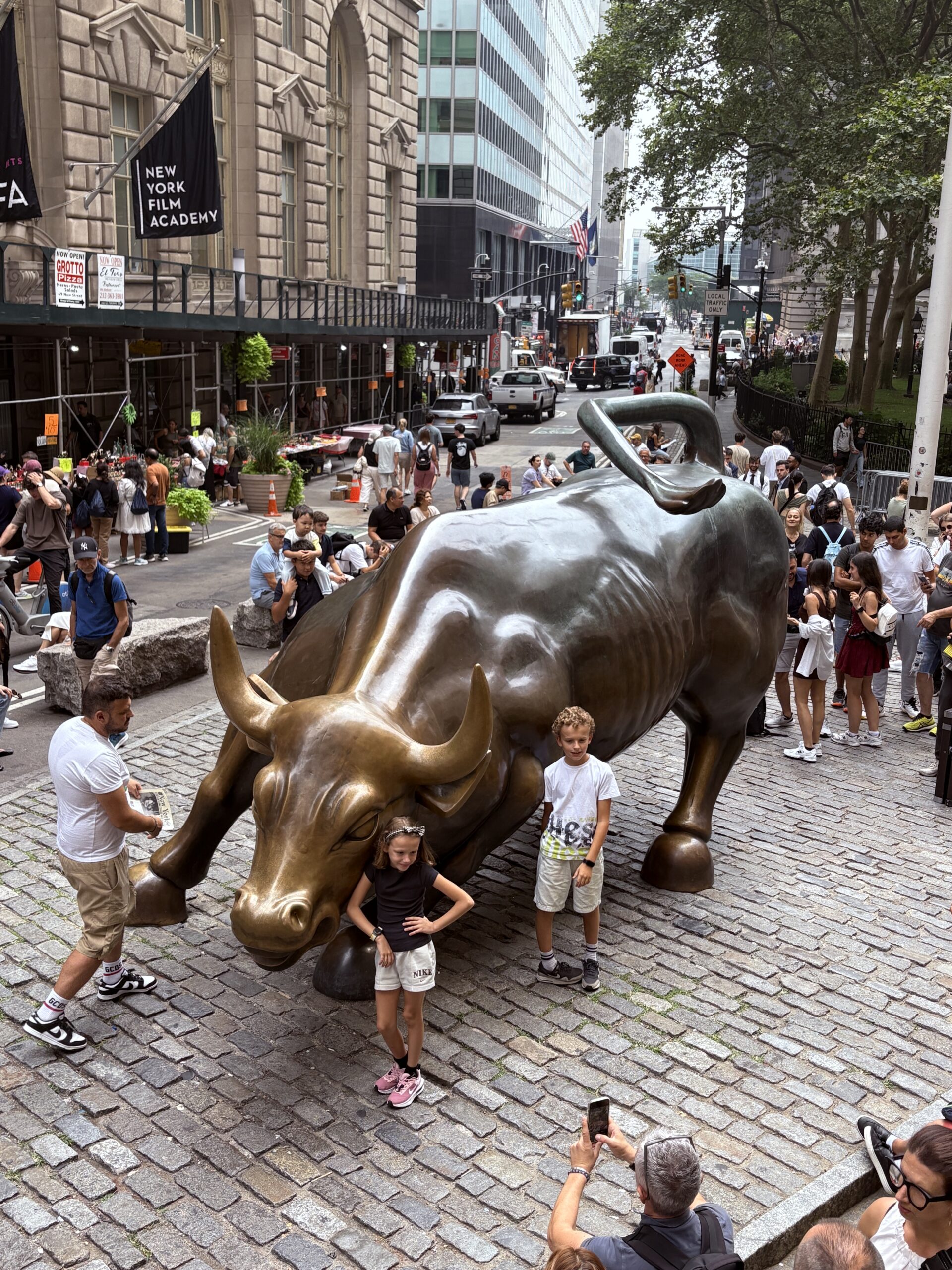 Charging Bull statue in New York City surrounded by tourists taking photos.
