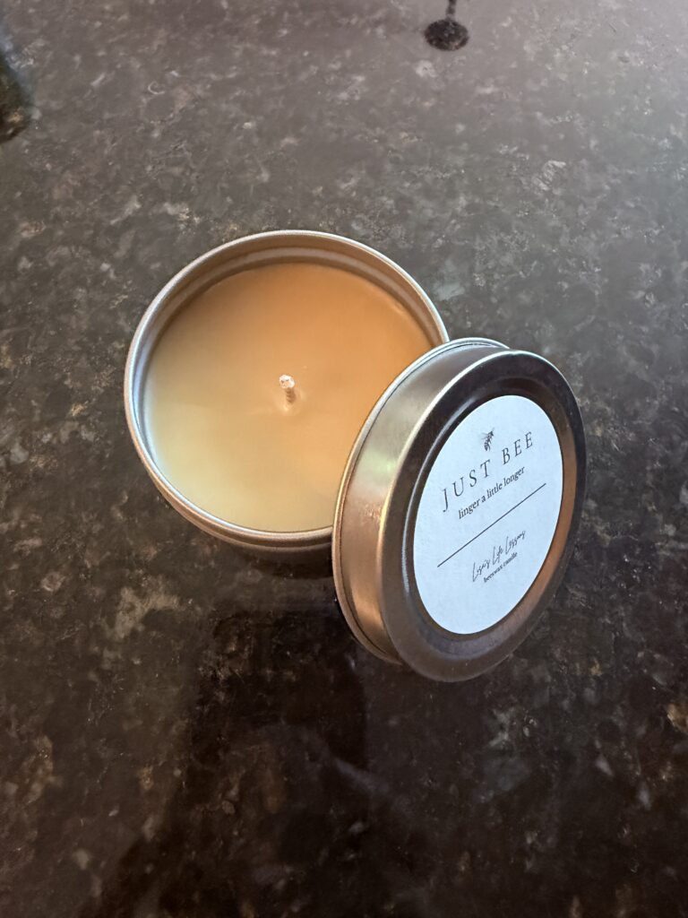 Small gold tin beeswax candle with a minimalist label reading “Just Bee – linger a little longer” by Lisa’s Life Lessons.